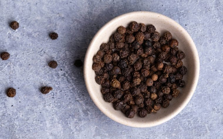 Whole black peppercorns in a bowl